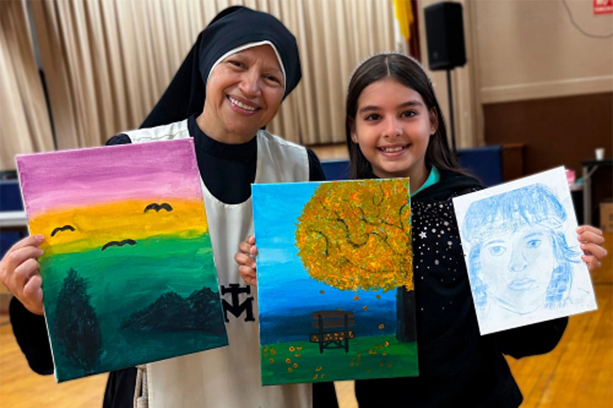 Young girl proudly showing her artwork alongside the religious sister leading the art program in Brooklyn.
